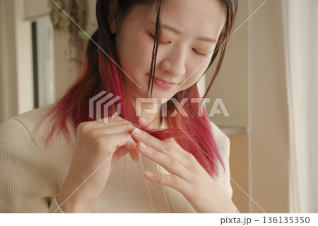 傷んだ髪の毛を気にする若い女性 136135350