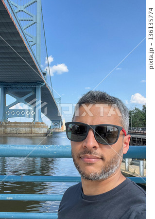 Benjamin Franklin bridge is a suspension bridge, and the water below is calm Benjamin Franklin bridge is a suspension bridge, and the water below is calm 136135774