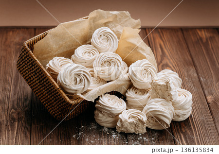 White meringue cookies in wicker basket on rustic wooden table White meringue cookies in wicker basket on rustic wooden table 136135834