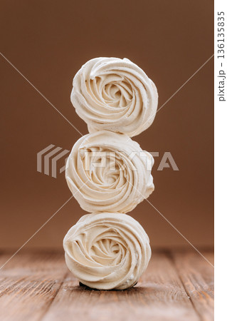 Stacked vanilla meringue swirls on wooden table, brown background Stacked vanilla meringue swirls on wooden table, brown background 136135835
