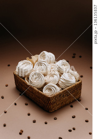 White meringue rosettes in wicker basket with coffee beans, beige copy space White meringue rosettes in wicker basket with coffee beans, beige copy space 136135837