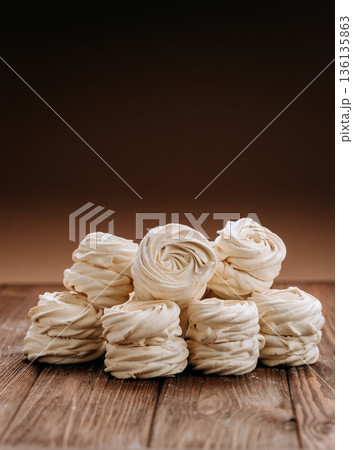 White meringue swirls stacked on rustic wooden table with copy space 136135863