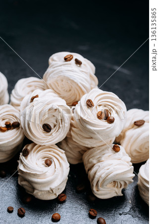 Coffee bean topped meringue cookies on dark slate with copy space 136135865