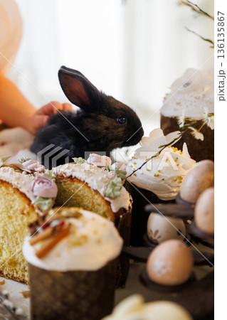 Black baby bunny with sliced Easter cake and festive spring dessert table 136135867