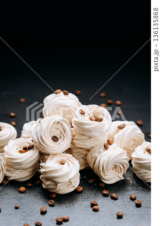 Vanilla zephyr meringue cookies with coffee beans on dark slate background Vanilla zephyr meringue cookies with coffee beans on dark slate background 136135868