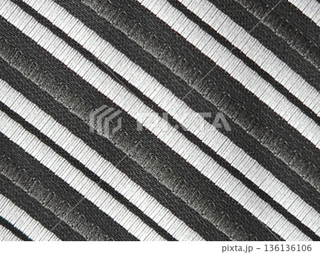 A close-up of the fabric of a men's tie with diagonal black and silver stripes. Accessory is made of microfiber 136136106