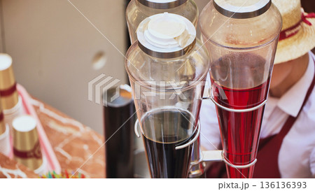 Vendor serving fresh flavored beverages in glass dispensers at street food stall Vendor serving fresh flavored beverages in glass dispensers at street food stall 136136393