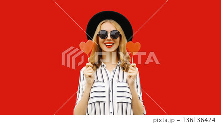 happy cheerful young woman with sweet red heart shaped lollipop on stick 136136424