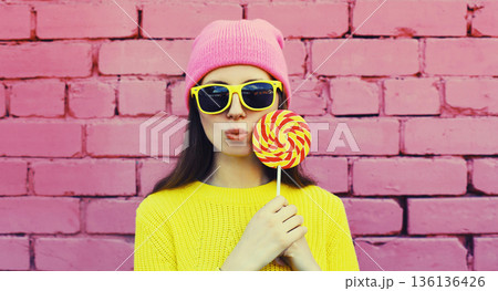 stylish modern young woman with lollipop in colorful clothes 136136426