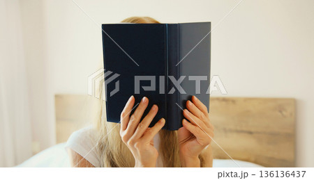 Young sad tired woman student with open book lying on the bed at home Young sad tired woman student with open book lying on the bed at home 136136437