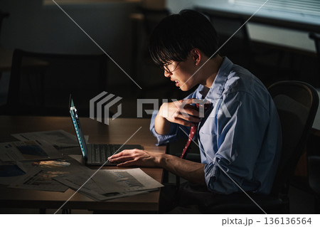 深夜まで仕事が終わらなくて残業をする若いビジネスマン 136136564