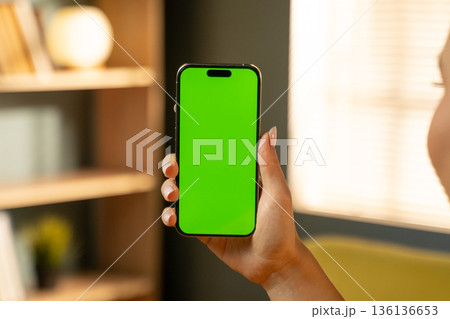 Person holding a mobile phone with a chroma key green screen, suitable for displaying various apps, videos, or messages, highlighting concepts of technology, connectivity, and communication 136136653