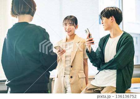 スマホを持ちながら談笑をする若い男女 スマホを持ちながら談笑をする若い男女 136136752
