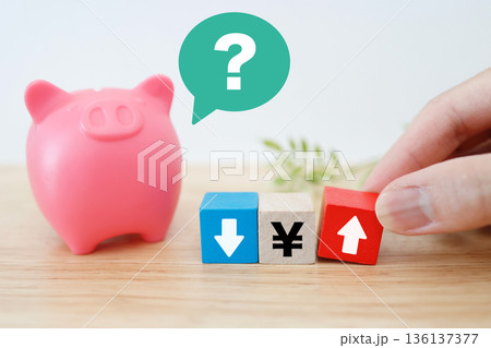 円高か円安かを考える貯金箱と矢印のイメージ。 円高か円安かを考える貯金箱と矢印のイメージ。 136137377