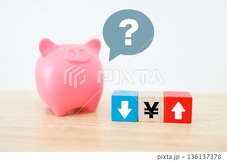 円高か円安かを考える貯金箱と矢印のイメージ。 円高か円安かを考える貯金箱と矢印のイメージ。 136137378