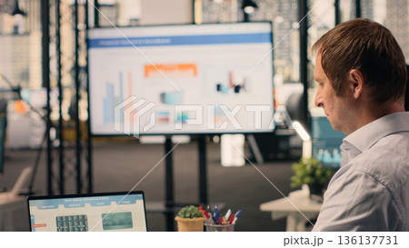 Working alone in office, businessman does analysis, charts and graphs, KPI on laptop. Business intelligence, analytics and insights, productivity, organizational strategy, development goals. 136137731