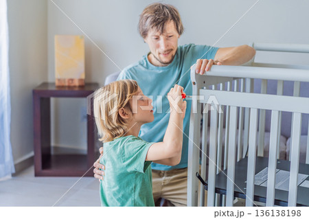 Father and older brother assembling a baby crib at home, preparing for a newborn arrival. Warm family moment full of care and anticipation. Parenthood, sibling bond and home preparation concept Father and older brother assembling a baby crib at home, preparing for a newborn arrival. Warm family moment full of care and anticipation. Parenthood, sibling bond and home preparation concept 136138198