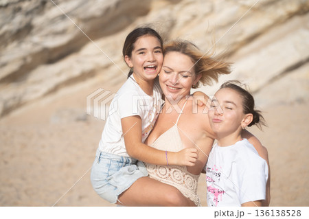 Loving mother embracing daughters on beach in Loving mother embracing daughters on beach in 136138528