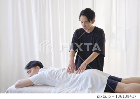 男性の腰をマッサージするマッサージ師 136139417