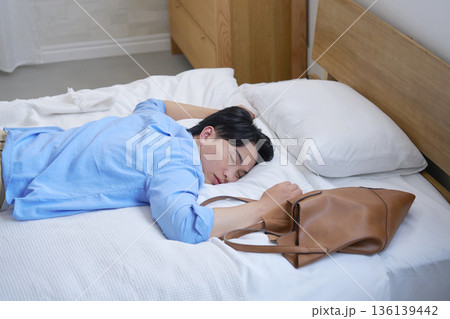 私服でベッドで寝る疲労した男性 136139442