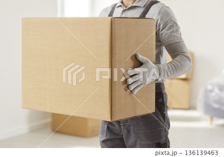 Close-up of mover holding large cardboard box during residential relocation Close-up of mover holding large cardboard box during residential relocation 136139463