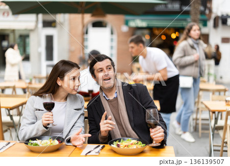 Girl in cafe sits near male companion, has nice conversation and discusses news of day 136139507