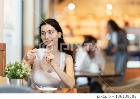 Girl whiles away time and waits for meeting in chain cafe 136139588