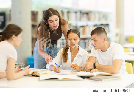 Group of students reading books and taking notes in library 136139601
