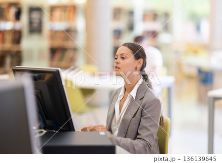 Young female student working on computer in library Young female student working on computer in library 136139645