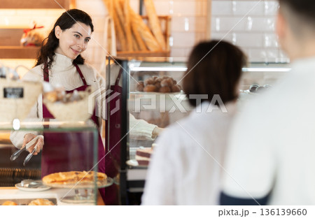 Young woman giving pastry to customer in cafe Young woman giving pastry to customer in cafe 136139660