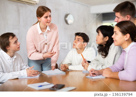 Young female tutor teaching group of students in college 136139794