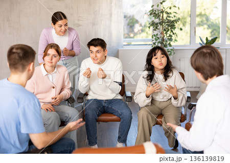 Group of students sitting in circle studying together in study hall of university 136139819