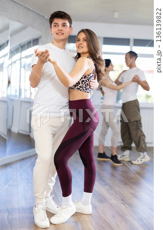 Dance studio - students in casual clothes learn to dance tango Dance studio - students in casual clothes learn to dance tango 136139822