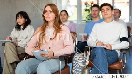 Young female student listening to lecture with focus Young female student listening to lecture with focus 136139883