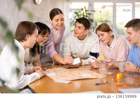 Smiling girls and boys play board games in classroom 136139909