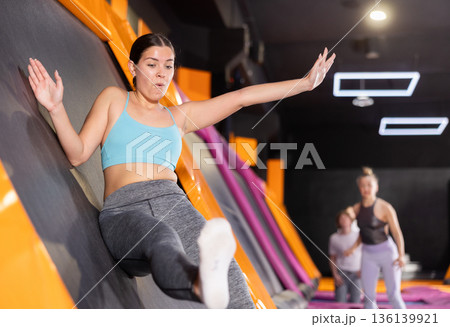 Young woman trains jumping in trampoline center 136139921