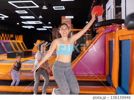 Young woman playing ball in trampoline center Young woman playing ball in trampoline center 136139946