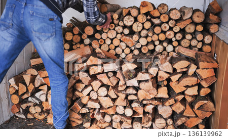 A man unloads firewood from a truck by hand. 136139962