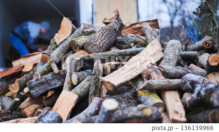 A man unloads firewood from a truck by hand. A man unloads firewood from a truck by hand. 136139966