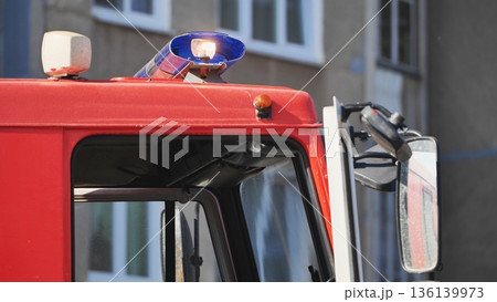 Red fire truck flashing lights and siren standing by on duty outside building Red fire truck flashing lights and siren standing by on duty outside building 136139973