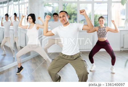 Guy enjoys active dancing, learns new movements, moves synchronously with participants of lesson Guy enjoys active dancing, learns new movements, moves synchronously with participants of lesson 136140097