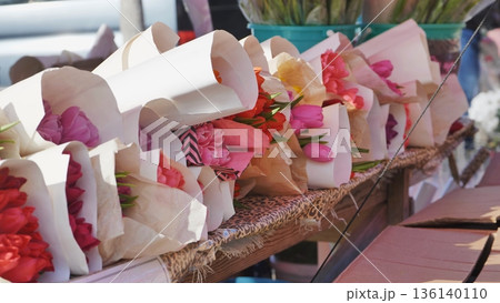 Wrapped tulip bouquets for sale at a flower market stall 136140110