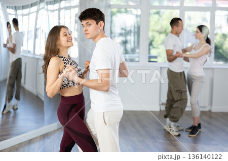 Dance training in group - young men and women dance salsa or bachata in dance studio 136140122