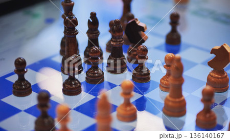 Wooden chess pieces standing on blue and white chessboard during a chess game 136140167