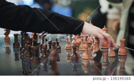 Wooden chess pieces standing on a reflective surface during a chess game 136140168