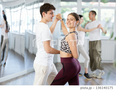Young man engaged in dance hall with female partner and dances Latin rumba during training. Hobby lifestyle concept 136140175