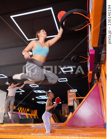 Young woman playing ball in trampoline center Young woman playing ball in trampoline center 136140194