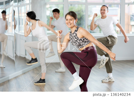 Smiling girl energizing group during dance fitness class Smiling girl energizing group during dance fitness class 136140234