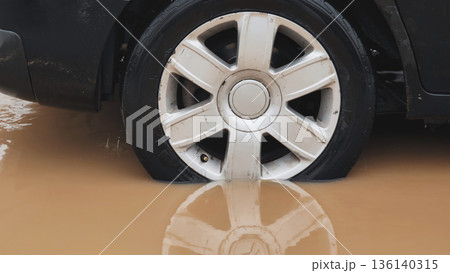 Car wheel stuck in muddy floodwater during heavy rain and storm Car wheel stuck in muddy floodwater during heavy rain and storm 136140315