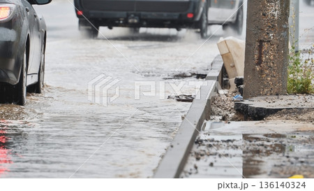 Cars driving through deep puddles on a flooded street during heavy rain 136140324